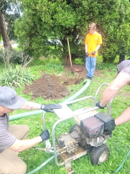 Bob's Septic Service crew using field equipment while servicing a residential septic system.