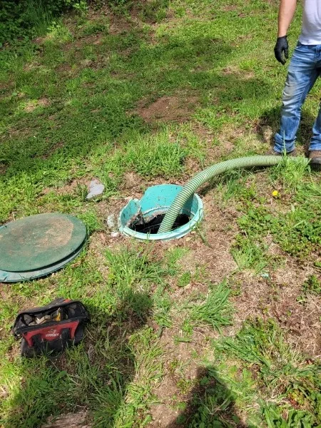 Open septic tank access lid with service hose during pumping and inspection work.